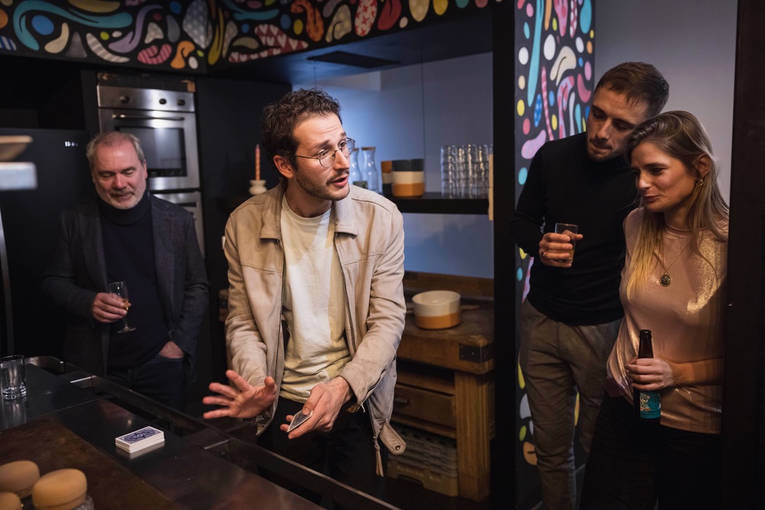 Magicien réalisant un tour de cartes dans un bar.